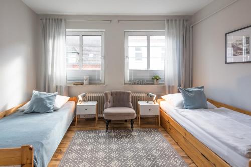 Habitación con 2 camas, silla y ventanas. en Onkel Theodor, en Husum