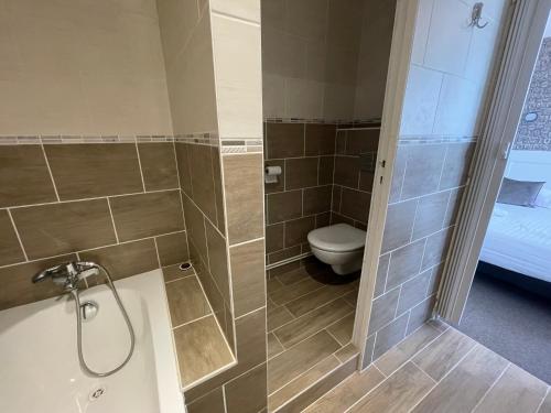 a bathroom with a shower and a toilet and a tub at Le Clos Normand in Saint-Aubin-sur-Mer