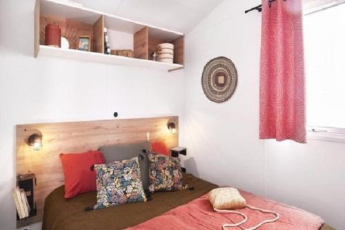 a bedroom with a bed with a red blanket and pillows at Camping Brin d'Amour in Les Eyzies-de-Tayac