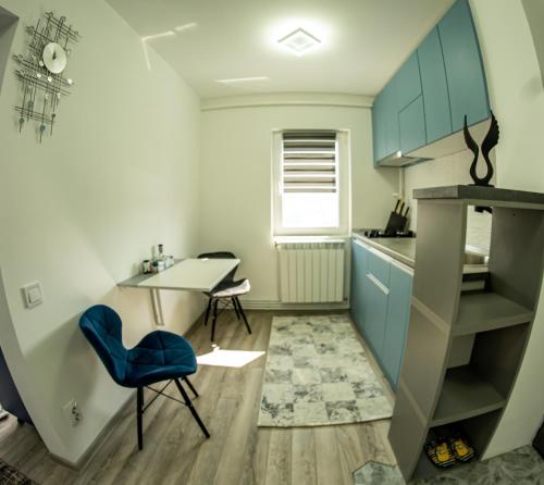una pequeña cocina con mesa y silla azul en Studio Lupul, en Petrila