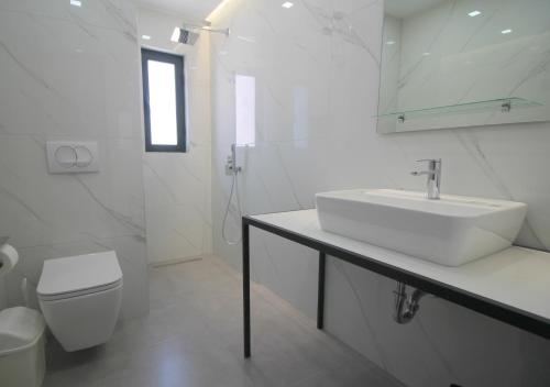 a white bathroom with a sink and a toilet at Olympia Hotel in Sarandë