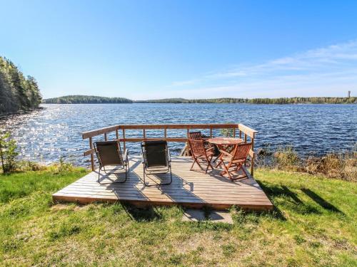a wooden dock with chairs and a table on a lake at Holiday Home Lahdeke by Interhome in Kotalahti