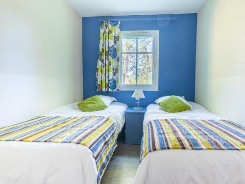 Cette chambre comprend 2 lits dans une chambre dotée de murs bleus et d'une fenêtre. dans l'établissement Holiday Home Domaine Golf Resort-3 by Interhome, à Lacanau-Océan