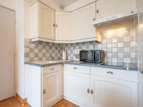 une cuisine avec des armoires blanches et un micro-ondes dans l'établissement Apartment Les Balcons de la Plage-5 by Interhome, à Canet