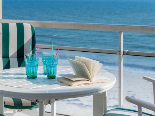 a table with an open book and two glasses of water at Apartment Morgane by Interhome in Saint-Pierre-Quiberon