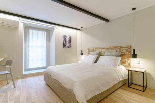 a white bedroom with a large bed and a window at Crociferi Luxury Apartment in Catania
