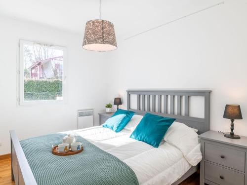 Schlafzimmer mit einem Bett mit blauen Kissen und einem Tisch in der Unterkunft Apartment Les Jardins d'Oihana by Interhome in Bidart
