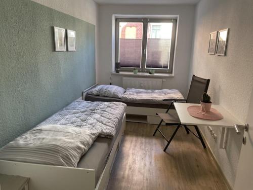 two beds in a room with a desk and a table at Wohnung am Markt - auch für Monteure gut geeignet in Stendal