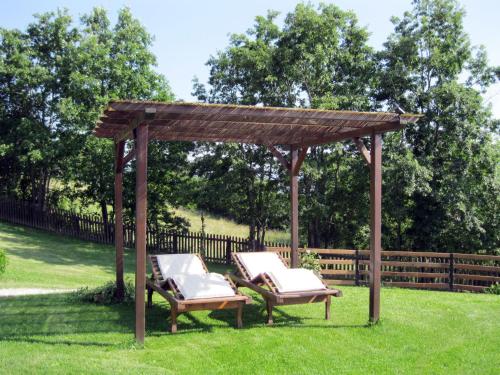 a wooden gazebo with two chairs in the grass at Apartment Il Girasole by Interhome in Piazza al Serchio