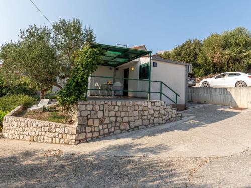 a small house with a stone retaining wall and a fence at Holiday Home Dubra by Interhome in Komarna