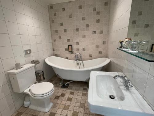 a bathroom with a tub and a toilet and a sink at Waxholms Hotell in Vaxholm