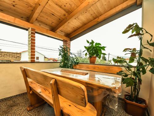 una mesa de madera y un banco en una habitación con ventanas en Apartment Zorić by Interhome, en Privlaka