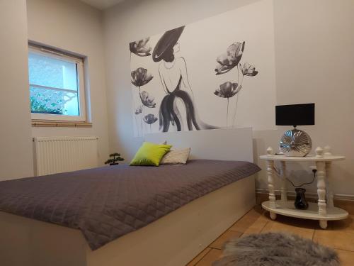 een slaapkamer met een bed met een schilderij aan de muur bij Apartament Przy Ratuszu in Boguszów-Gorce