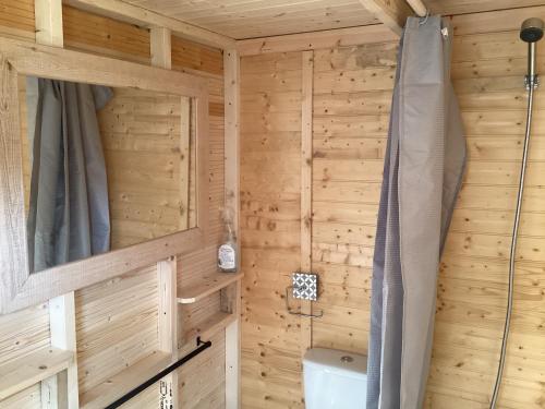 y baño con pared de madera, ducha y aseo. en Vigo Retreat cabin 1, en Sevenoaks