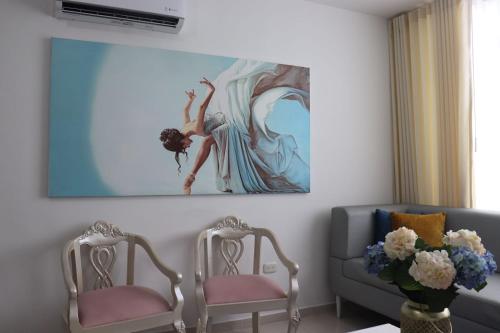a living room with two chairs and a painting on the wall at Apartamento a 15 min de BUENAVISTA cerca a UNINORTE y CLINICA PORTOAZUL AA 2TV y parqueadero incluido in Barranquilla