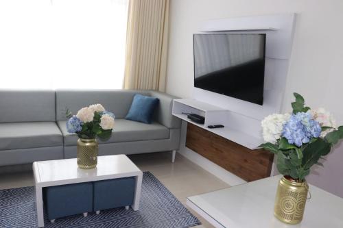 una sala de estar con dos jarrones con flores. en Apartamento a 15 min de BUENAVISTA cerca a UNINORTE y CLINICA PORTOAZUL AA 2TV y parqueadero incluido en Barranquilla