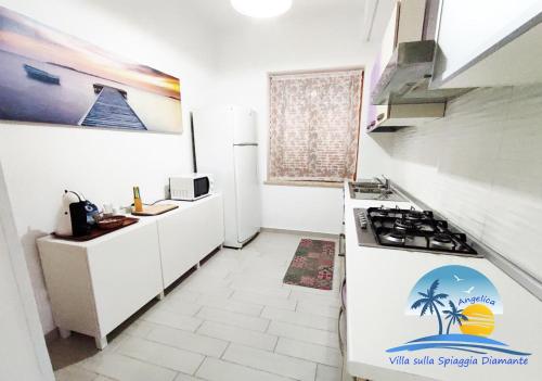 uma cozinha branca com um fogão e um frigorífico em Villa sulla Spiaggia Diamante em Belvedere Marittimo