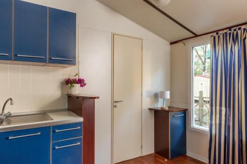 a kitchen with blue cabinets and a window at Comfort Lodge Maremma in Grosseto
