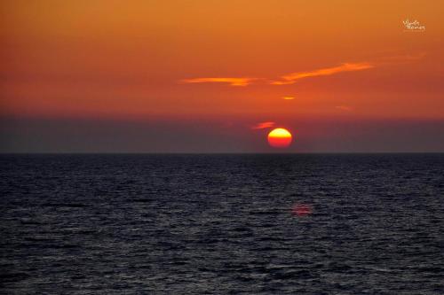 a sunset over the ocean with the sun setting at Sunset Cottage in Paramonas