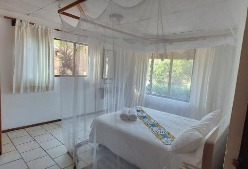 a white bedroom with a bed and a window at Bay View Lodge in Miramar