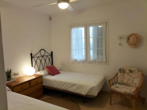 a bedroom with two beds and a chair and a window at Grupoandria Villa Julia in Cala en Forcat