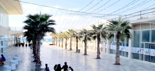 people walking in a mall with palm trees at Hotel Apartment Short Term Tel Aviv Bat Yam 5 in Bat Yam