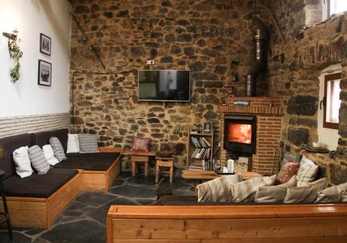 a living room with a stone wall with a fireplace at Albergue El Rebezo in Torrebarrio