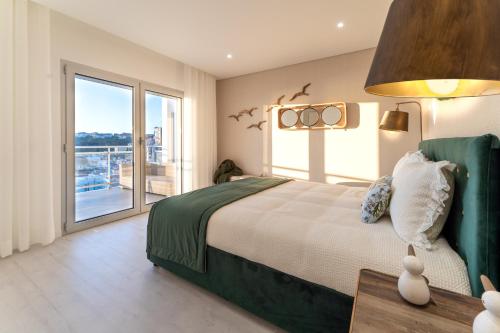 een slaapkamer met een groot bed en een groot raam bij T3 Pelican Bay in Nazaré
