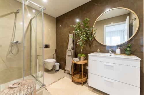 een badkamer met douche, wastafel en spiegel bij T3 Pelican Bay in Nazaré