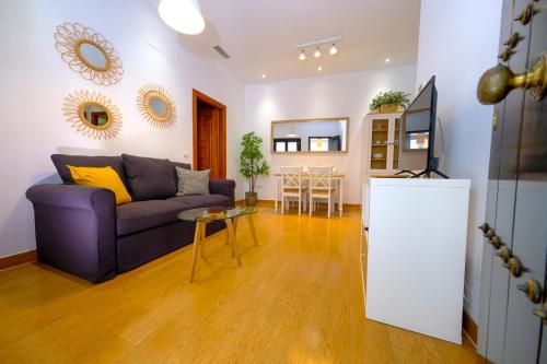 een woonkamer met een paarse bank en een tafel bij Patio Rialto Apartment in Sevilla