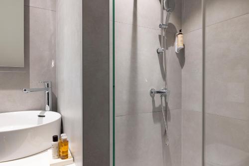 La salle de bains est pourvue d'une douche en verre et d'un lavabo. dans l'établissement Hôtel Du Dragon, à Strasbourg