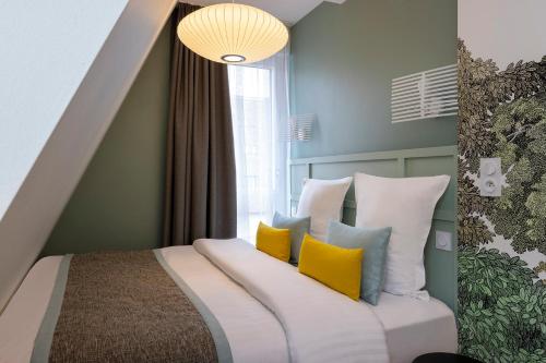 a bedroom with a bed with yellow and blue pillows at Hôtel Du Dragon in Strasbourg