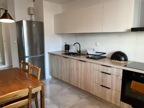a kitchen with a stainless steel refrigerator and a table at Vizja Apartments Kolska 9 in Warsaw