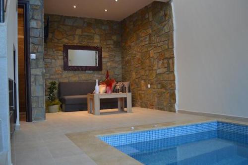 een woonkamer met een zwembad en een stenen muur bij Stone Suites in Pefkochori