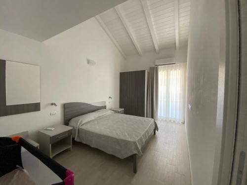 een witte slaapkamer met een bed en een raam bij Domus de Victoria in Càbras