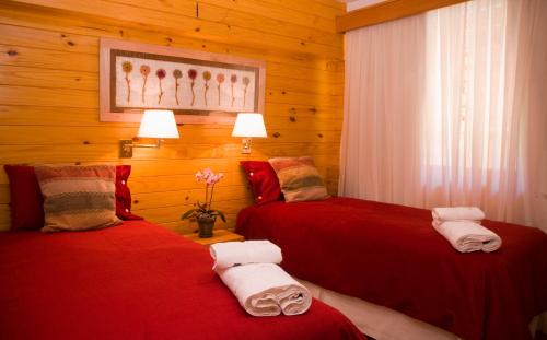 two red beds in a room with wooden walls at Apart del Faldeo in San Martín de los Andes