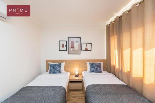 2 Betten in einem kleinen Zimmer mit blauen Kissen in der Unterkunft Prime Select Sheraton in Kairo