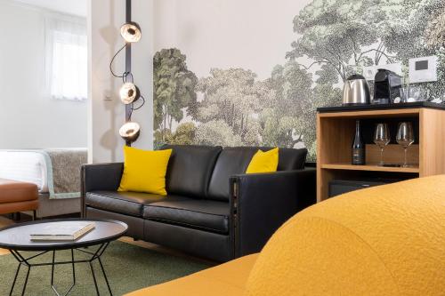 a living room with a black couch and yellow pillows at Hôtel Du Dragon in Strasbourg