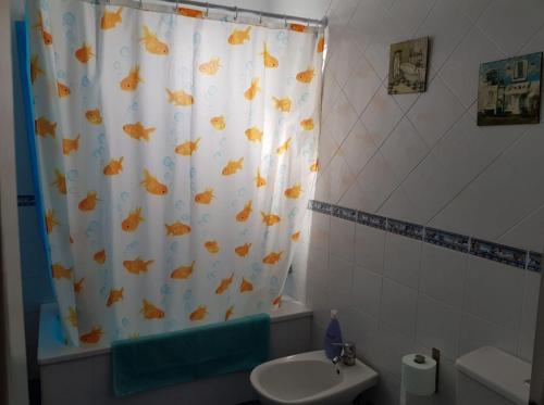 a bathroom with a shower curtain with a toilet and a sink at Pura vida en Sevilla in Seville