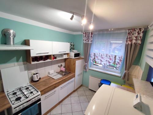 a small kitchen with white cabinets and a window at Domek,Nocleg pod Skrzycznym Szczyrk in Szczyrk