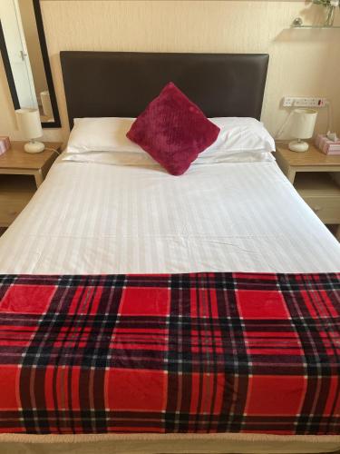 a bed with a red pillow on top of it at Diamonds Lodge near York Hospital in York