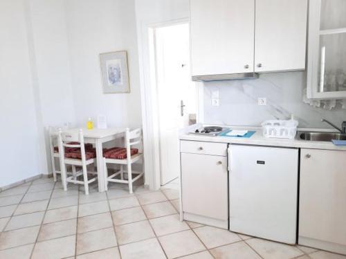 a kitchen with a table and white cabinets and a table and chairs at Panorama Apartments Fiscardo in Fiskardho