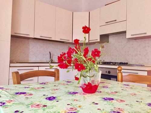 a vase with red flowers on a table in a kitchen at LES PETITES MAISONS Maison rouge in Procida