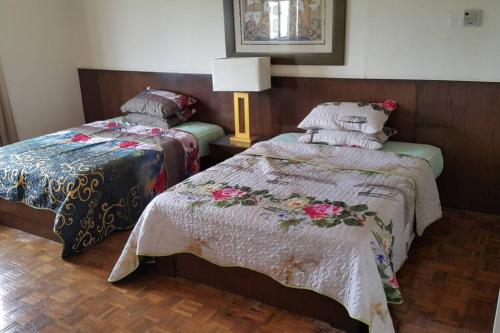 a bedroom with two beds and a lamp at D Savoy 3 Bedroom Condo within Famosa Resort in Kampong Alor Gajah