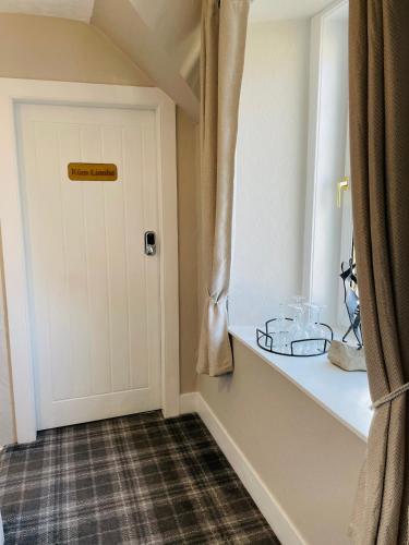 a room with a door and a shelf with glasses on it at Whinburn Guest House in Fort William