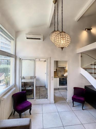 d'un salon avec des chaises violettes et un lustre. dans l'établissement Duplex 6 à 7 personnes, 100 m des plages du midi, Cannes, à Cannes