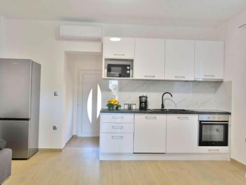 una cucina con armadi bianchi e frigorifero in acciaio inossidabile di Fancy Apartments Dream a Brna