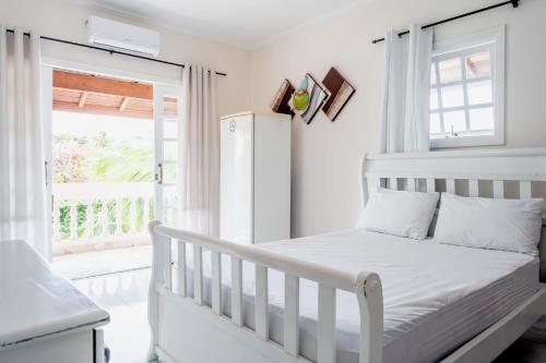 a white crib in a white bedroom with a window at Pousada Oásis in Peruíbe
