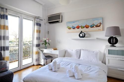 a white bedroom with a bed and a desk and a window at Glyfada Breeze Apartments in Athens