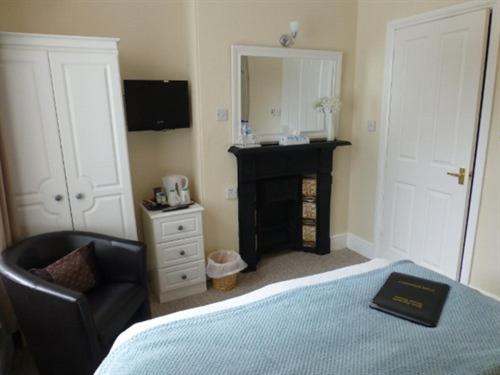 a bedroom with a bed and a chair and a mirror at Bryn Derwen Guest House in Conwy